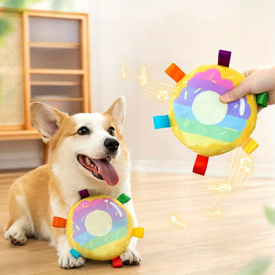 Cartoon plush flying disc dog toy with colorful tabs for outdoor play and training, shown with happy corgi indoors
