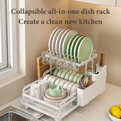 White collapsible all-in-one kitchen dish rack with multiple tiers holding plates, bowls, cups, and utensils on countertop near sink