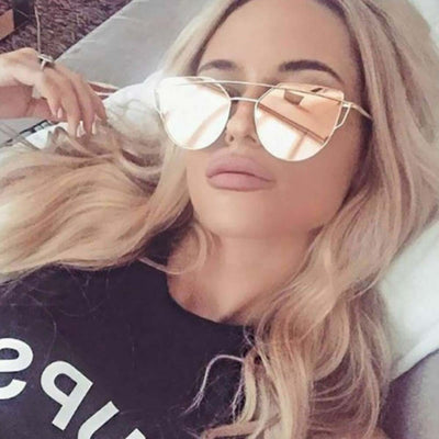 Woman wearing oversized frames cat-eye sunglasses with gold metal frame and pink mirror reflective lenses