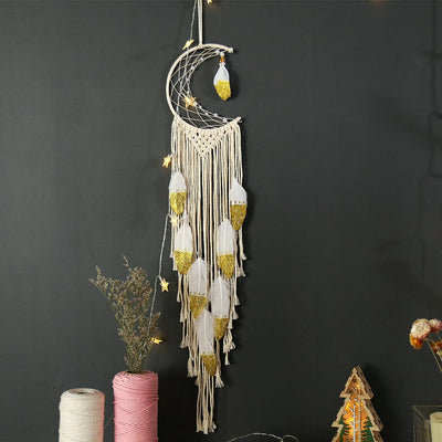 Crescent dream catcher wall decor with cotton thread and gold-accented feathers hanging against a dark background