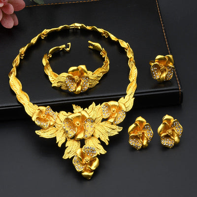 Saudi women's necklace, bracelet, earrings, and ring set in golden alloy with rhinestones, featuring a floral design.