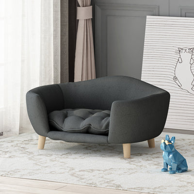 Dark gray fabric dog bed with tufted cushion and birch wood legs in modern living room setting